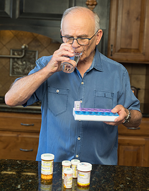 Man taking pills in kitchen.