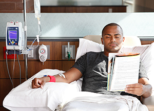 Man reading while having chemotherapy infusion.