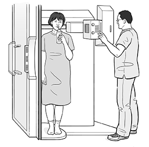 Woman standing in fluoroscopy scanner sipping liquid through a straw while healthcare provider prepares for scan.