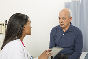 Hombre que habla con un proveedor de atención médica en la sala de exámenes.